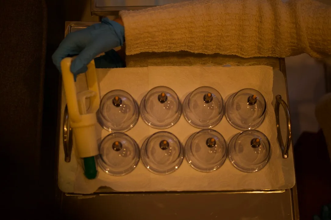 Cupping cups laid out on a tray, with a gloved hand holding the hand pump.